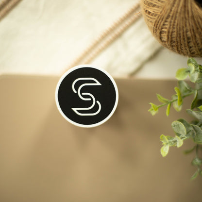 A circular vinyl sticker of the Stickr logo on a fancy background