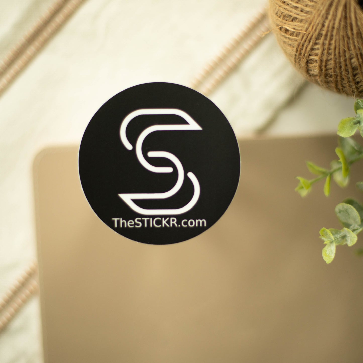 A circular black vinyl sitcker with the Stickr logo and website on a fancy background