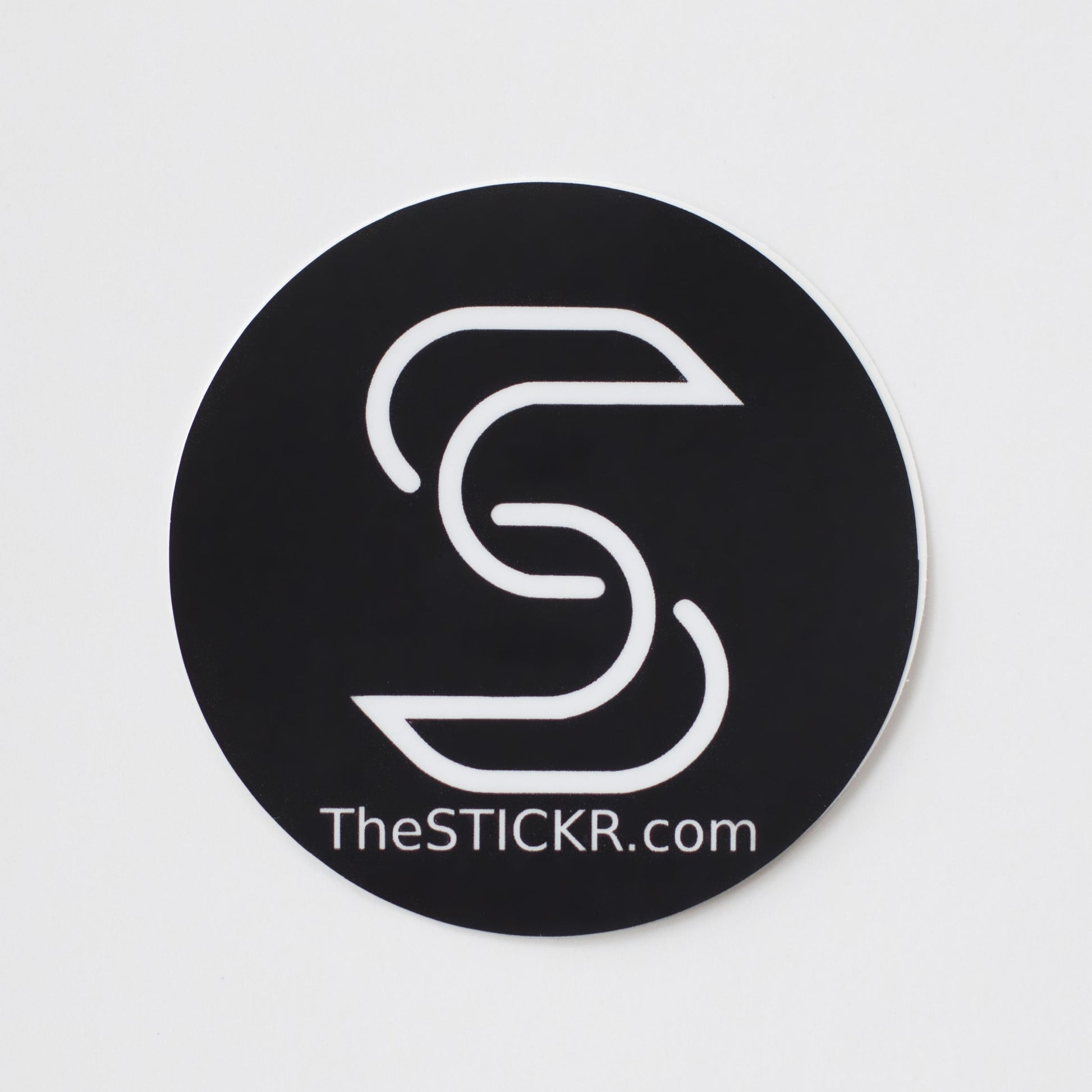 A circular vinyl sticker of the Stickr logo and website on a white backgorund