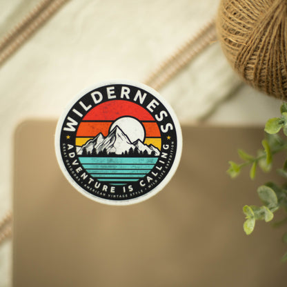 A circular, vinyl sticker of a colorful mountain landscape in front of a fancy background