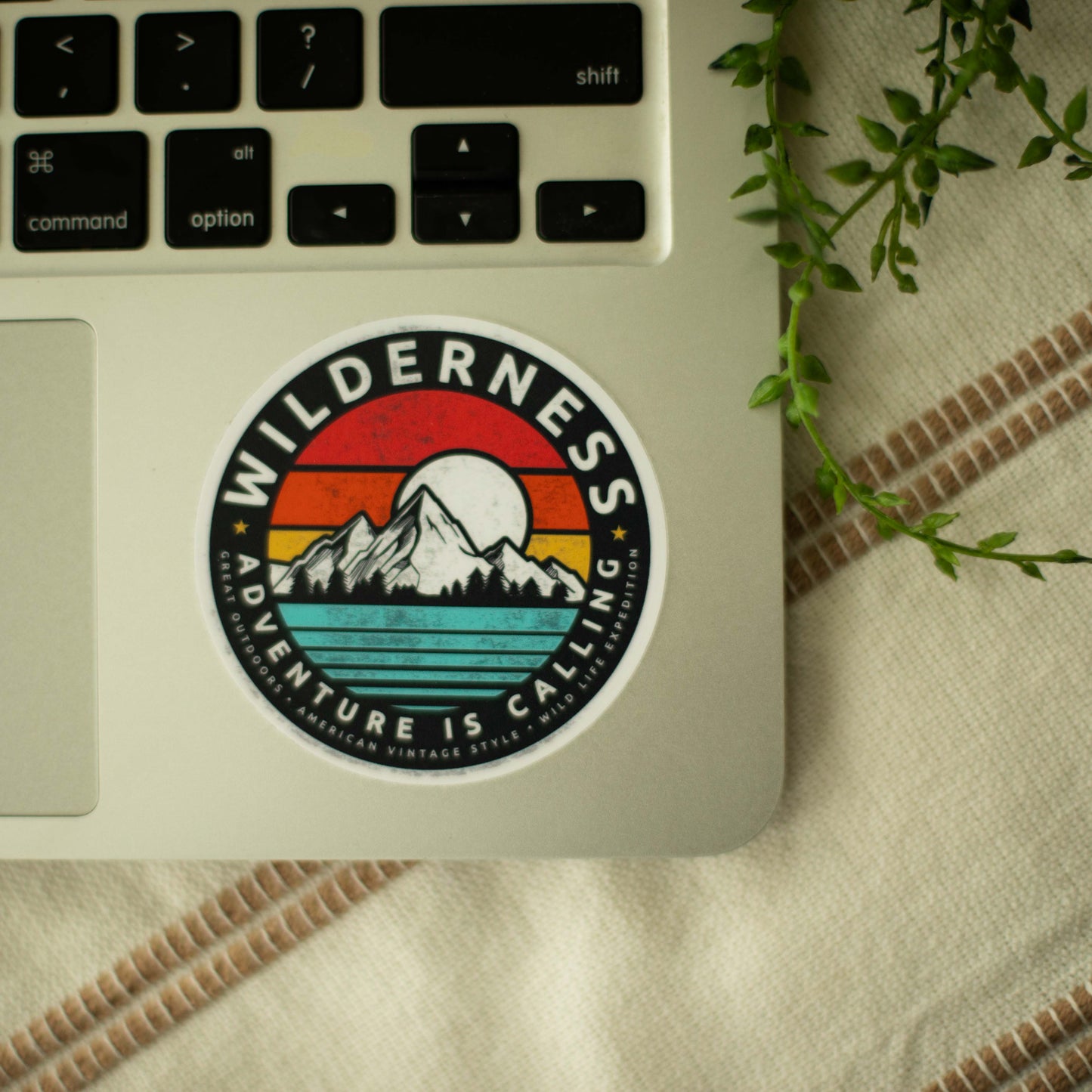 A colorful circular vinyl sticker of a mountain landscape on a laptop