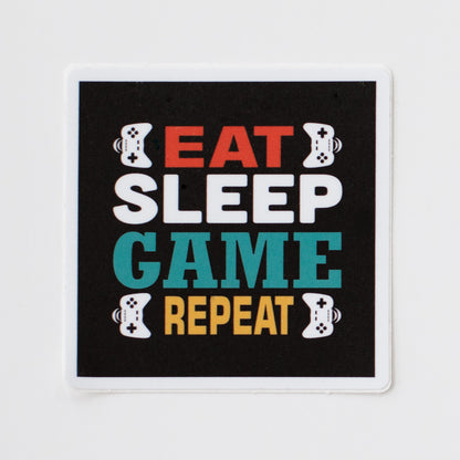 A square-shaped sticker with the words eat sleep game repeat and images of game controllers on a white background