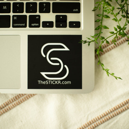 A square-shaped black and white vinyl sticker of the Stickr logo and website on a laptop