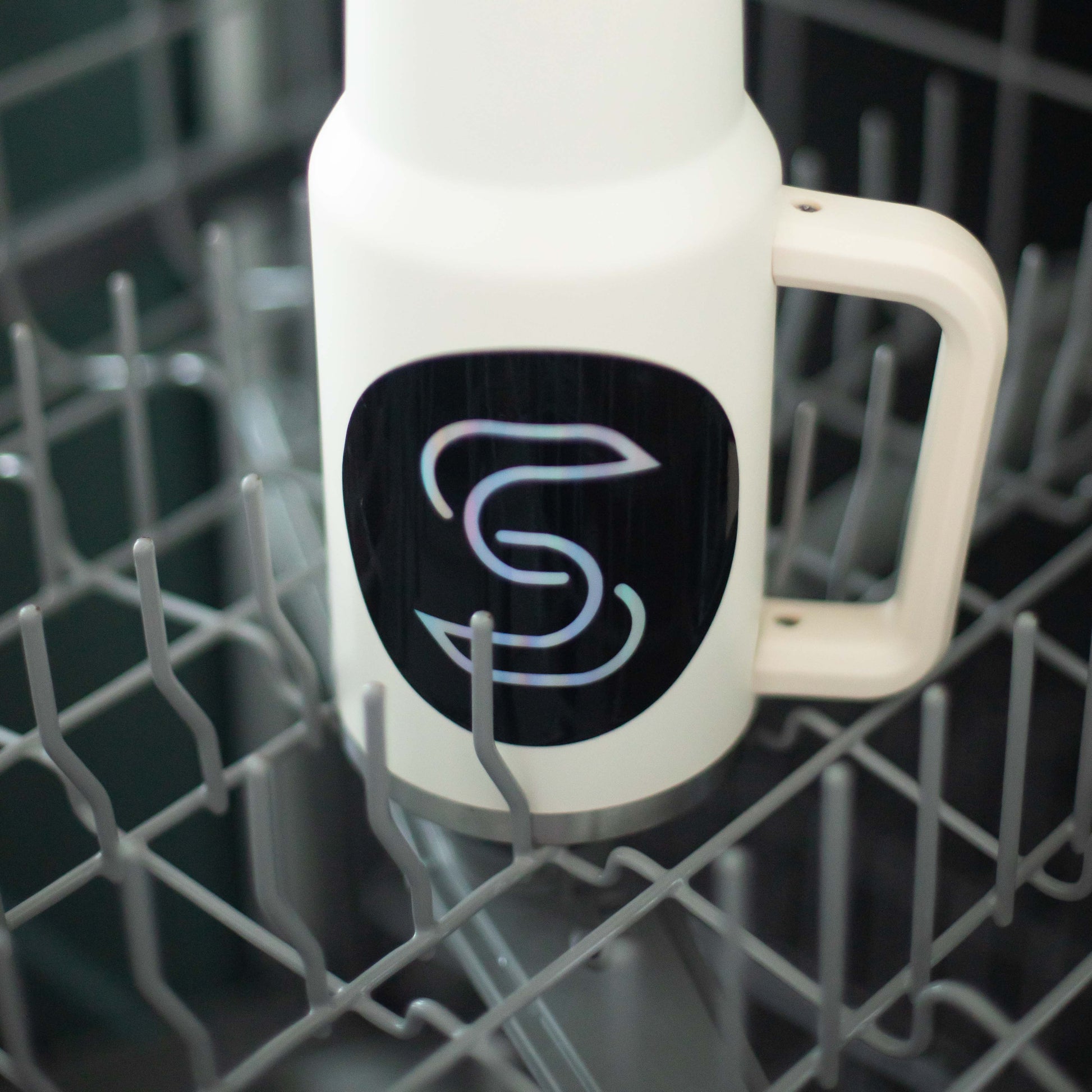 A holographic sticker of the Stickr logo on a water bottle in a dishwasher