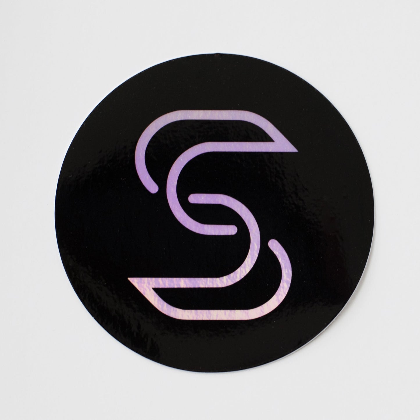 A holographic sticker of the Stickr logo on a white background